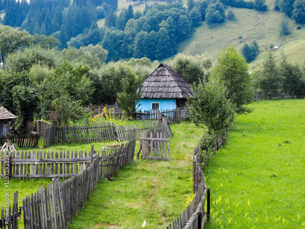 An old house set on a hill with wooden fences 